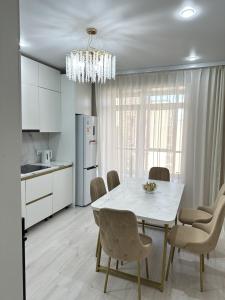 a kitchen and dining room with a white table and chairs at ПОЛНОЦЕННАЯ ТРЕХКОМНАТНаЯ ЛЮКС in Kokshetau