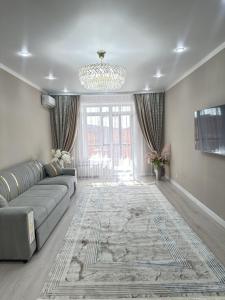a living room with a couch and a chandelier at ПОЛНОЦЕННАЯ ТРЕХКОМНАТНаЯ ЛЮКС in Kokshetau