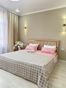 a bedroom with a large bed with pink sheets at ПОЛНОЦЕННАЯ ТРЕХКОМНАТНаЯ ЛЮКС in Kokshetau