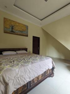 ein Schlafzimmer mit einem Bett und einem Gemälde an der Wand in der Unterkunft Stellar Cottage Lovina- a villa in Murni's house in Lovina