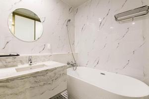 a white bathroom with a tub and a mirror at Gimhae Perfect Hotel in Gimhae +195 photos