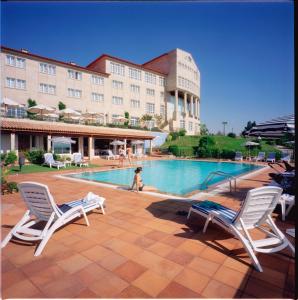 una piscina con 2 sillas y un edificio en Gran Hotel Los Abetos en Santiago de Compostela