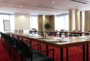 a large conference room with long tables and chairs at IntercityHotel Schwerin in Schwerin