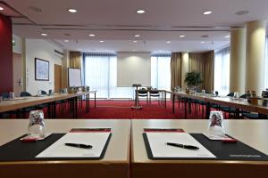 a conference room with long tables and chairs and a whiteboard at IntercityHotel Schwerin in Schwerin