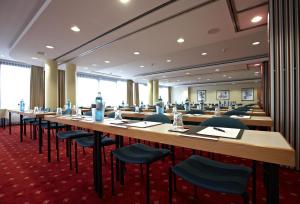 a large conference room with long tables and chairs at IntercityHotel Schwerin in Schwerin