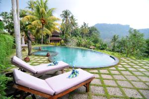 a pool in a resort with two chairs in front of it at Villa Karma Loka in Sidemen