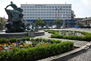 a statue in a park with flowers in front of a building at IntercityHotel Schwerin in Schwerin