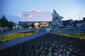 a building with a statue and flowers in front of it at IntercityHotel Schwerin in Schwerin