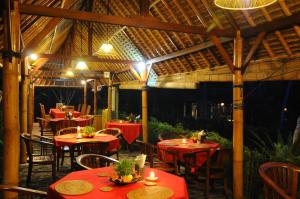 a dining area with tables and chairs and umbrellas at Villa Karma Loka in Sidemen