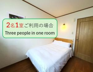 a room with a bed and a sign that reads three people in one room at やすらぎの宿フォーシーズン矢本 in Yamoto