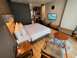 a bedroom with a bed and a table and a television at The Teak Hotel in Mae Sot