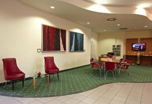 a waiting room with red chairs and a table at IntercityHotel Schwerin in Schwerin