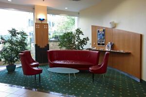 a waiting room with a red couch and two chairs at IntercityHotel Schwerin in Schwerin