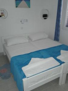 a bed with white sheets and a blue blanket at Apartment Tara in Nečujam