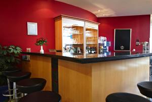 a bar in a restaurant with red walls and stools at IntercityHotel Schwerin in Schwerin +37 photos