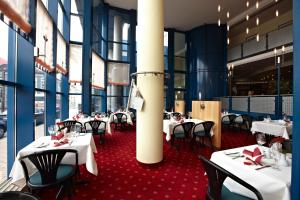 a dining room with white tables and black chairs at IntercityHotel Schwerin in Schwerin