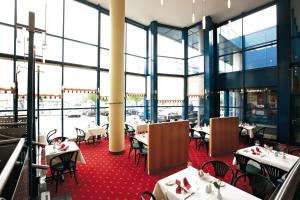 a restaurant with tables and chairs and large windows at IntercityHotel Schwerin in Schwerin