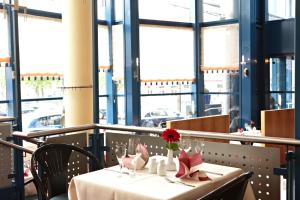 a table with a white table cloth and a red flower on it at IntercityHotel Schwerin in Schwerin