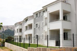 a white building with a fence in front of it at Apartments Crnekovic Tomislava 8 in Baška