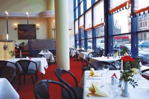 a restaurant with white tables and chairs and windows at IntercityHotel Schwerin in Schwerin