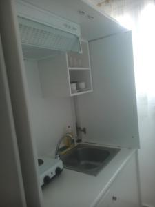 małą białą kuchnię ze zlewem i kuchenką w obiekcie Karagiozos Studios & Apartments w mieście Skopelos