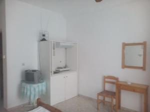 eine Küche mit einem Kühlschrank, einem Stuhl und einem Spiegel in der Unterkunft Karagiozos Studios & Apartments in Skopelos