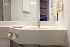 a bathroom with a white sink and a mirror at IntercityHotel Schwerin in Schwerin