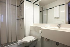 a bathroom with a toilet and a sink and a shower at IntercityHotel Schwerin in Schwerin