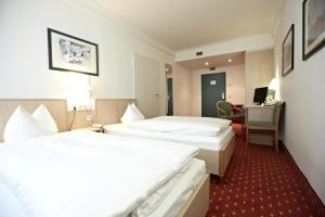 a hotel room with two beds and a desk at IntercityHotel Schwerin in Schwerin