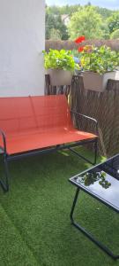 a red bench on a balcony with potted plants at Studio proche centre-ville in Autun