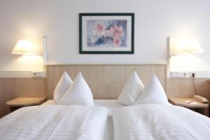 a hotel room with two beds with white pillows at IntercityHotel Schwerin in Schwerin