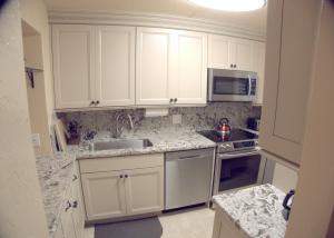a kitchen with white cabinets and a sink and a microwave at Menehune Shores 223 condo in Kihei