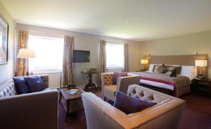 a hotel room with a bed and a couch and chairs at Stonefield Castle Hotel ‘A Bespoke Hotel’ in Stonefield