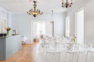 Habitación con mesas blancas, sillas blancas y lámpara de araña. en Stiftsgården Konferens & Hotell en Skellefteå
