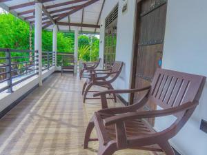 a row of wooden chairs sitting on a porch at Yala Zafiro in Kataragama +21 photos