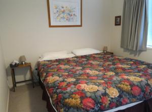 a bedroom with a bed with a floral quilt at K West in Kuaotunu