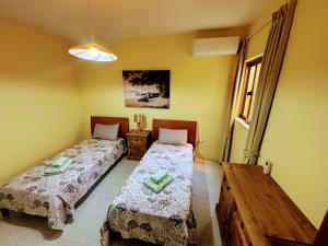 two beds in a room with yellow walls at SeaView Sunset Gozo in Marsalforn +1 photo