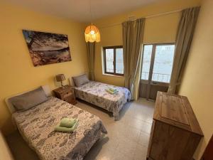 a bedroom with two beds and a table and windows at SeaView Sunset Gozo in Marsalforn