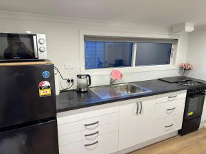 a kitchen with a black refrigerator and a sink at Matildas Apartment in Timaru