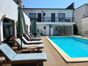 a pool with lounge chairs and umbrellas next to a building at Omega Mamaia Nord in Mamaia Sat/Năvodari