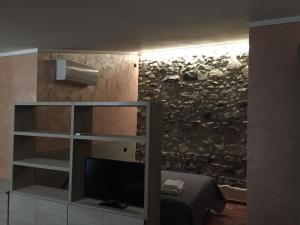 a room with a television and a wall with a stone wall at Hostel del Gal in Clusane sul Lago +49 photos
