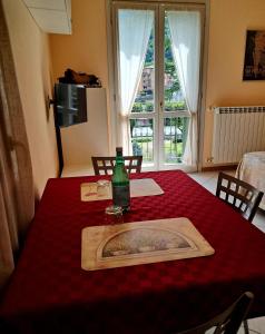 a table with a bottle on a red table cloth at Casa vacanze ELISA in San Pellegrino Terme