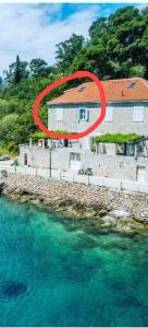 a house with a red circle in front of the water at Seafront apartment Marina2 in Jelsa