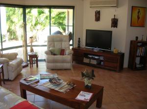 ein Wohnzimmer mit einem Sofa und einem TV in der Unterkunft Golden Cane Bed & Breakfast in Bargara