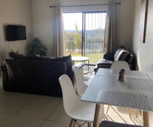Una sala de estar con un sofá, una mesa y sillas. en Warm, Homely Apartment - 5min Away Menlyn Main, en Pretoria