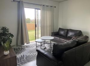 Una sala de estar con un sofá de cuero y una mesa. en Warm, Homely Apartment - 5min Away Menlyn Main, en Pretoria