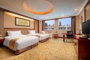 a hotel room with two beds and a television at Chutian Guangdong International Hotel in Wuhan