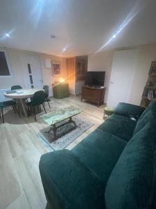een woonkamer met een groene bank en een tafel bij Maison cosy avec jardin & parking, proche Disney in Chelles