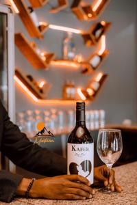 a person holding a bottle of wine and a glass at montana restaurant musanze in Ruhengeri