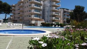 a large apartment building with a swimming pool and flowers at Apartamento Cap de Salou in Salou